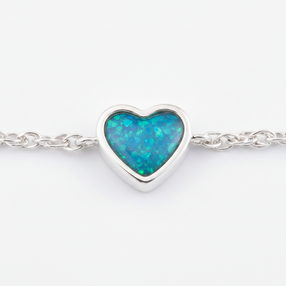 Close-up macro of heart bezel filled with blue teal opal resin showing silver channel border detail