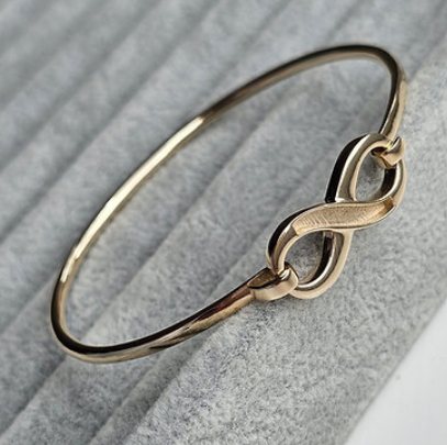 9ct yellow gold infinity hook clasp bangle full view on grey fabric