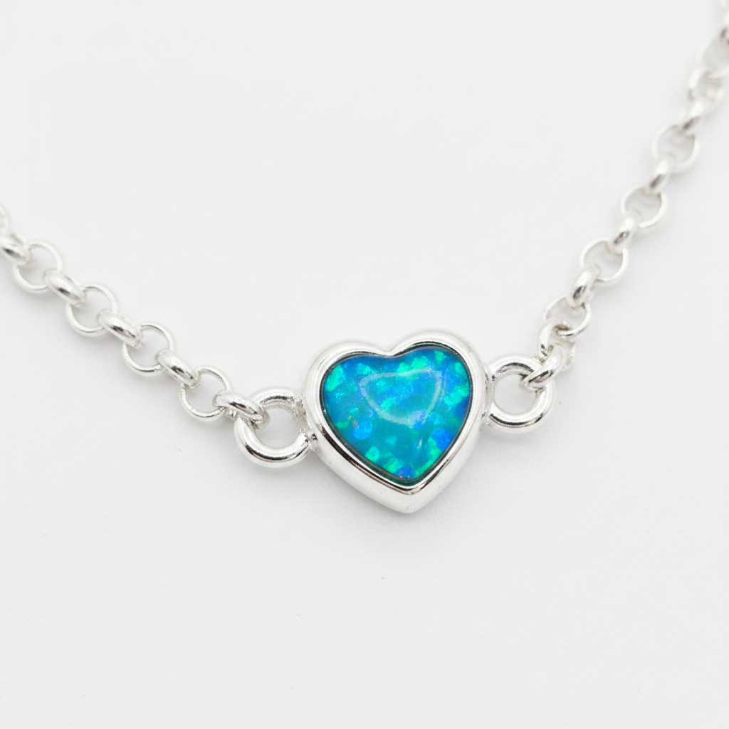 Mini heart charm silver bracelet close-up with blue teal opal resin in heart bezel, white background