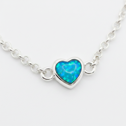Mini heart charm silver bracelet close-up with blue teal opal resin in heart bezel, white background