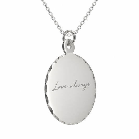 Illustrative handwriting engraving on scalloped oval silver pendant with sterling silver chain, on white background