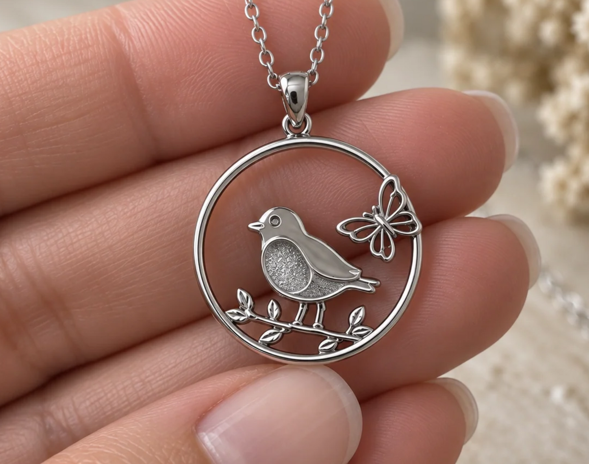 Robin and butterfly stainless steel pendant on chain, held between fingers