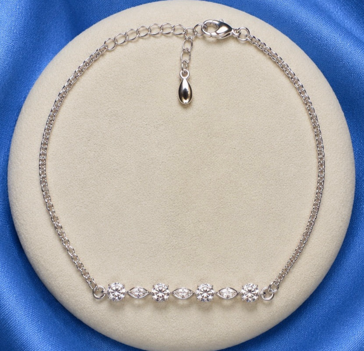 925 sterling silver CZ marquise bar bracelet on round jewellery display showing curved bar with alternating CZ rounds and marquise bezels on curb chain with adjustable extension and decorative pebble