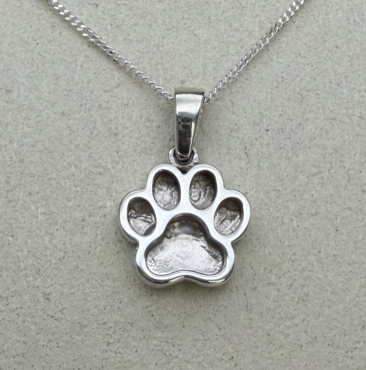 925 sterling silver petite paw print pendant close-up showing polished raised paw outline with one large central pad and four toe pad bezels