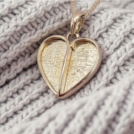 9ct yellow gold split heart pendant on white knit fabric showing two-section bezel centre