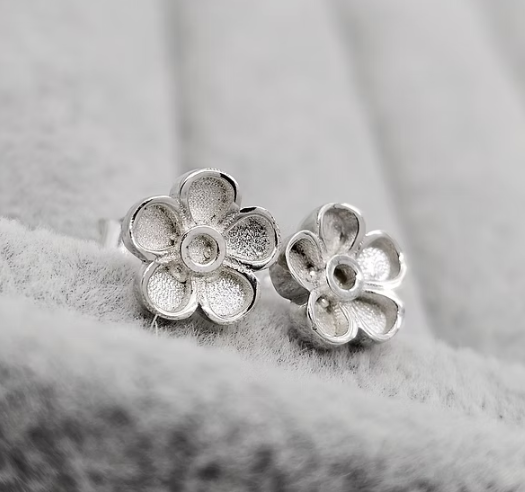 Silver 925 forget-me-not flower stud earrings angled on grey fabric — blank silver