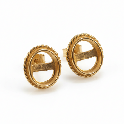 Pair of gold earrings with a logo on a beige fabric background