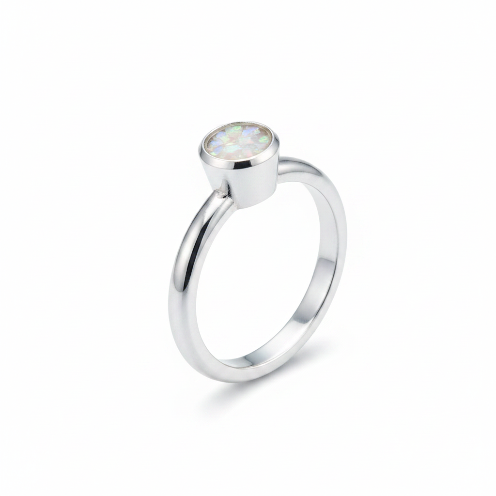 Handcrafted sterling silver rubover memorial ring with white pearl opal and mica shimmer in flat resin setting on white background