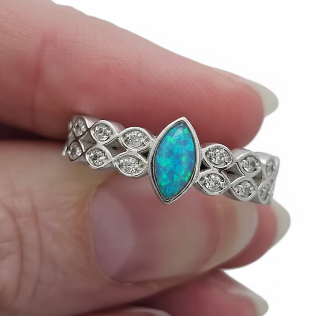 Double marquise band CZ 925 silver ring with blue teal opal resin held between fingers on white background