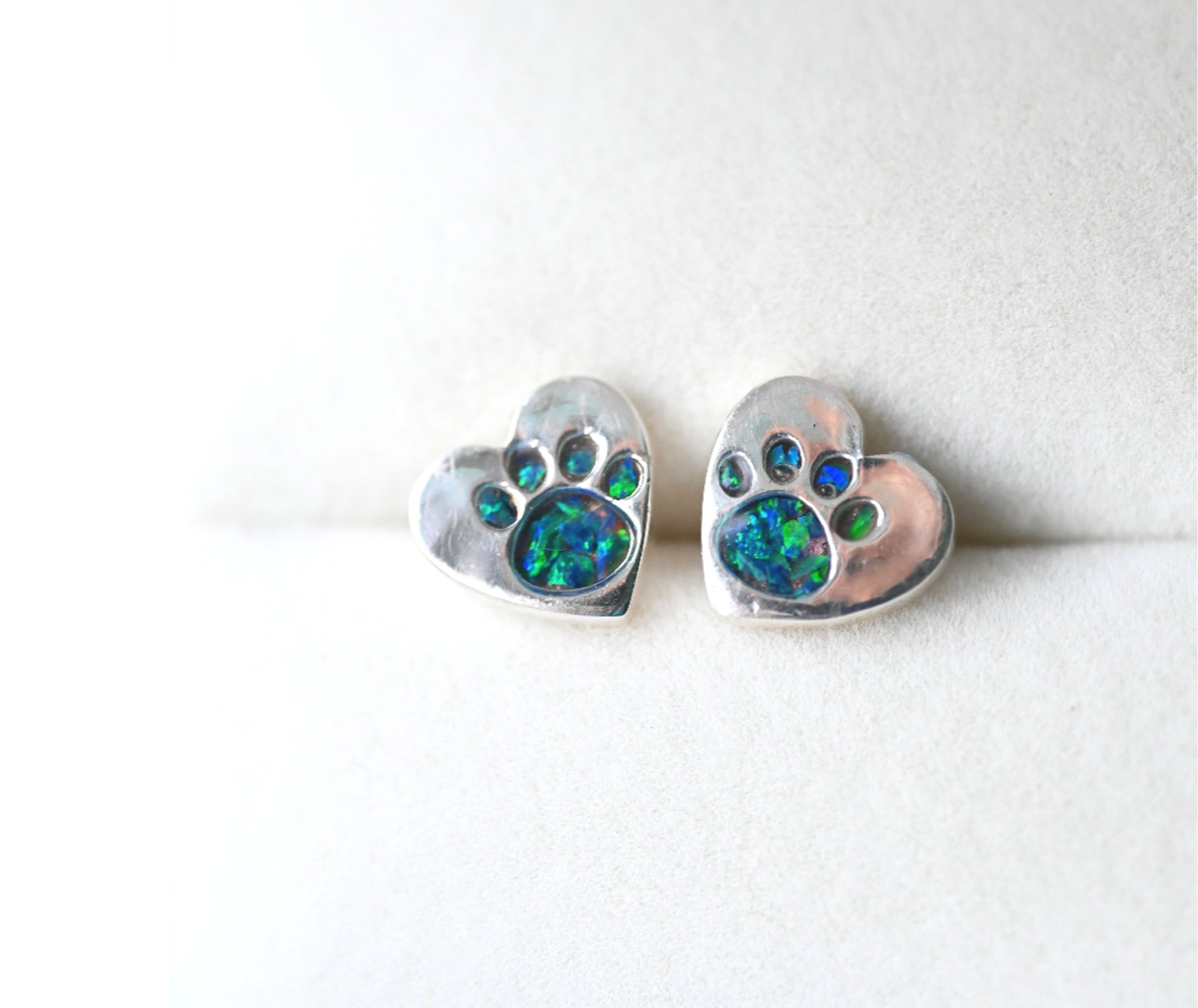 Close-up of sterling silver heart-shaped stud earrings (9mm) with tiny paw prints, symbolising the everlasting bond with a beloved pet.