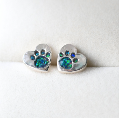 A pair of 9mm sterling silver heart-shaped stud earrings featuring delicate paw print engravings, designed as a heartfelt pet memorial keepsake.